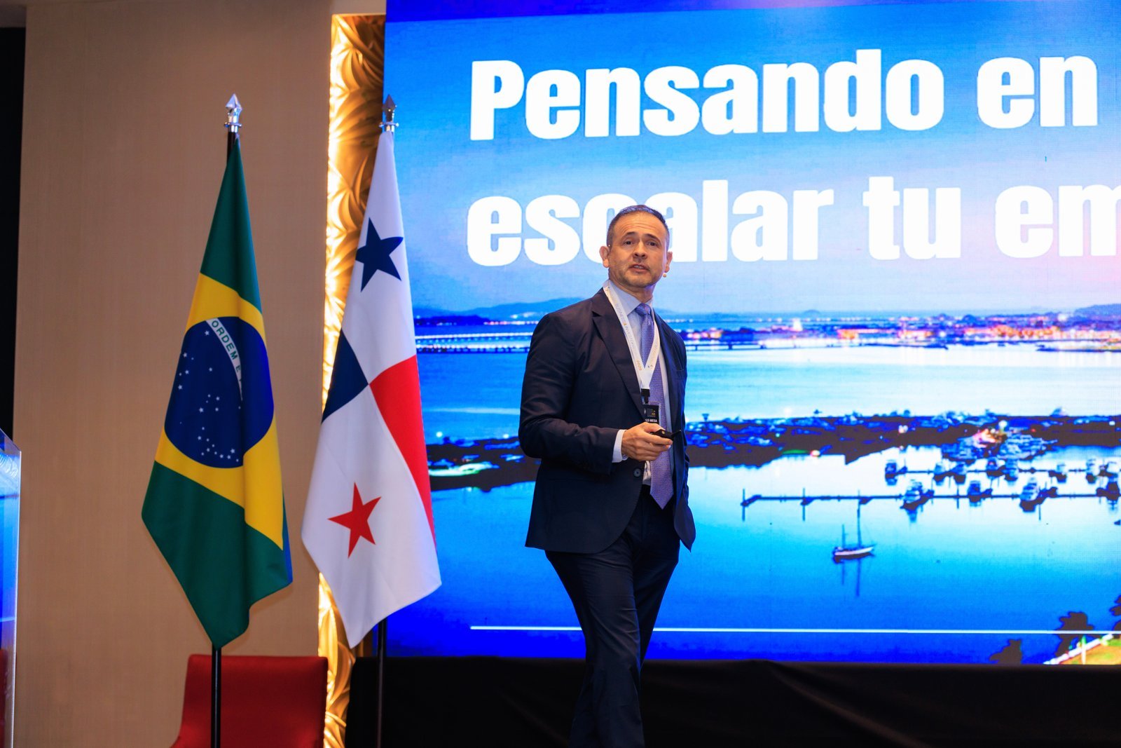 Harold Mesa presentando en un evento internacional entre las banderas de Brasil y Panamá